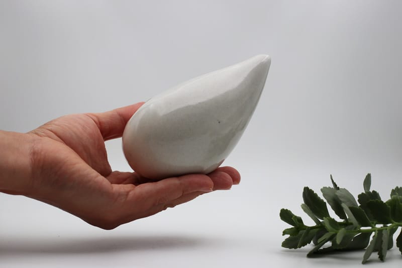 Angled view of the neti pot in a hand, showing the tip and contour